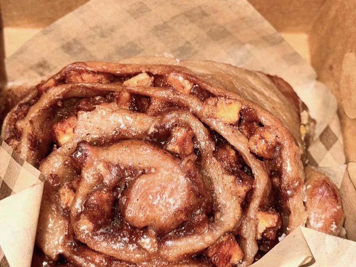 A glazed Southern cinnamon roll in a kraft box lined with gingham paper